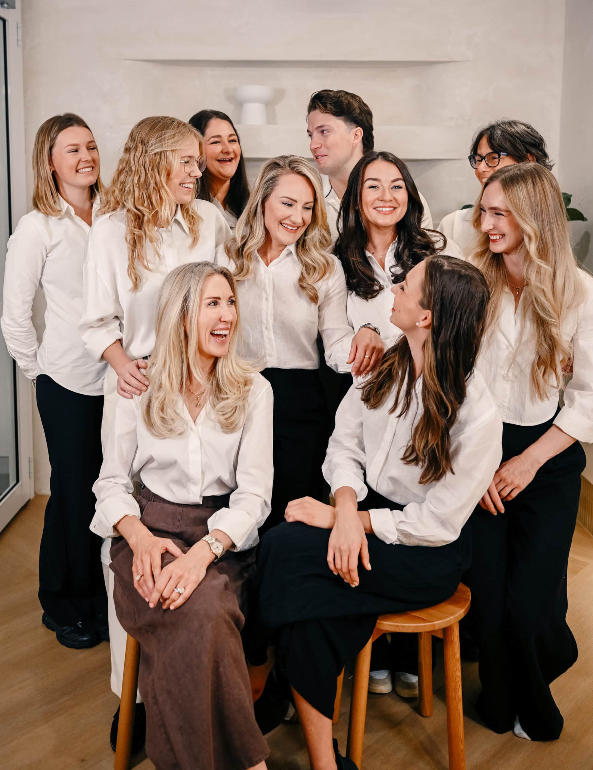 Friendly healthcare team standing and sitting together in a clinic, wearing white shirts, for the About Us team page