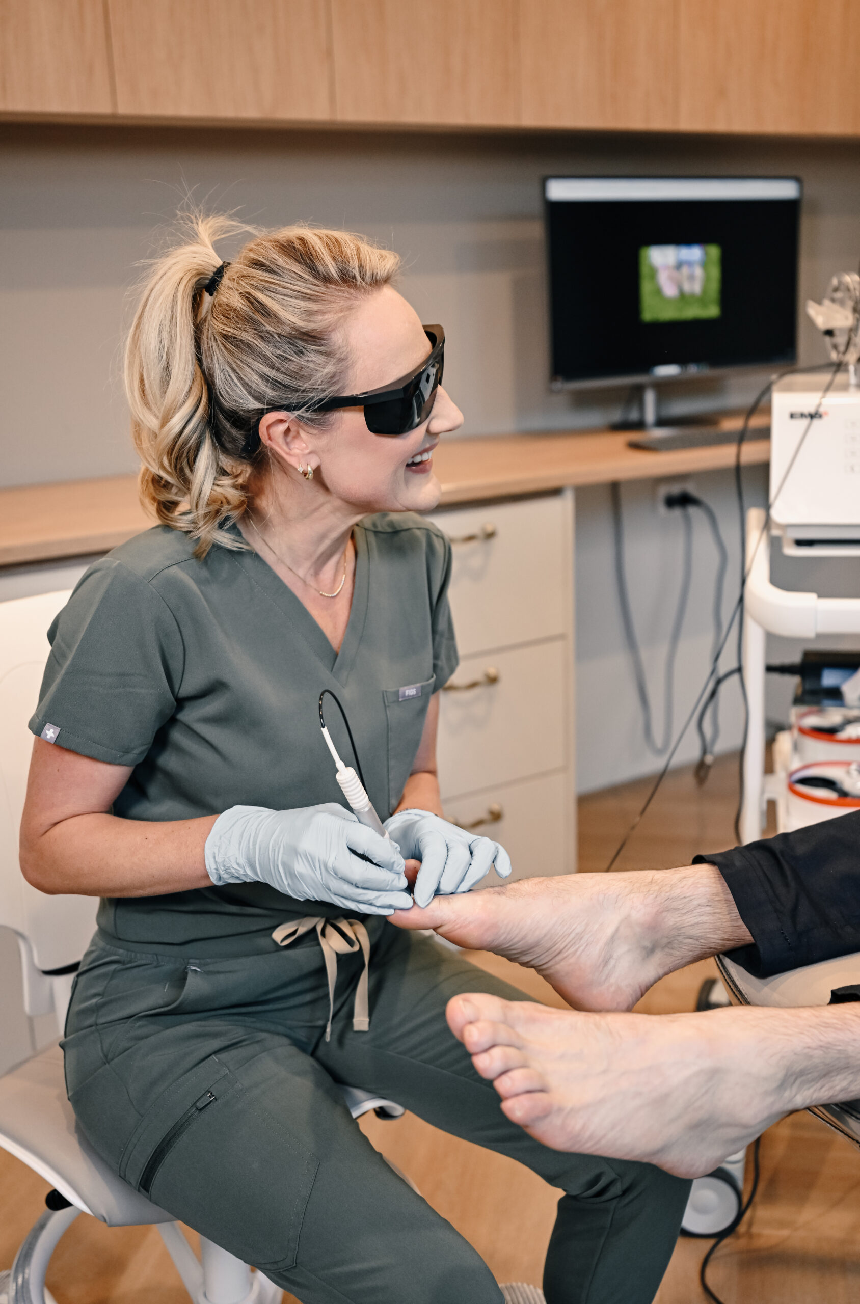 Podiatrist using fungal nail laser treatment on a patient’s toenail in a modern podiatry clinic